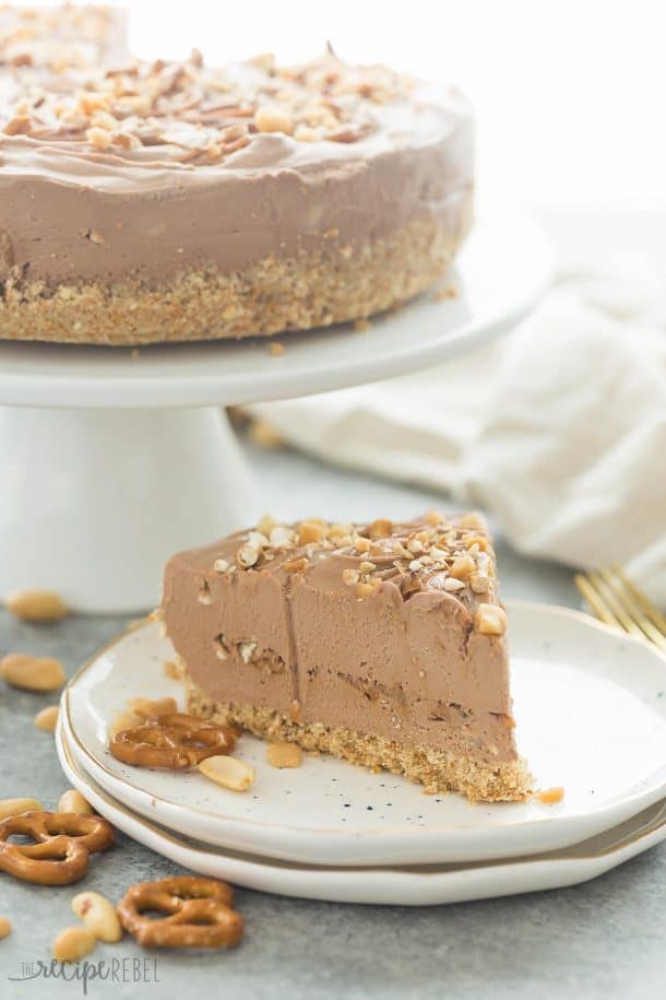 no bake chocolate peanut butter cheesecake slice on white speckled plate with whole cheesecake in the background