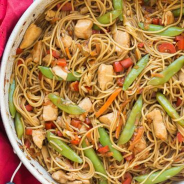 one pot chicken chow mein overhead on grey background with red towel on the side