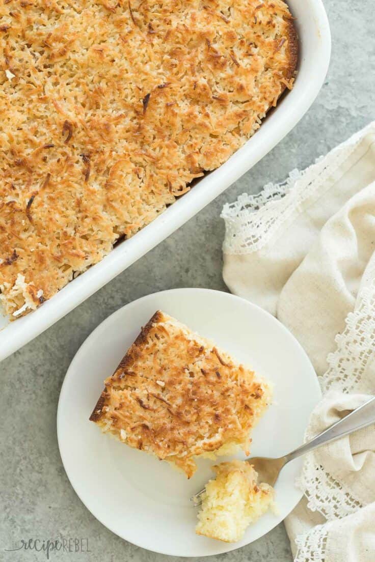 overhead image of hot milk cake with coconut frosting in white baking dish and one piece on white plate