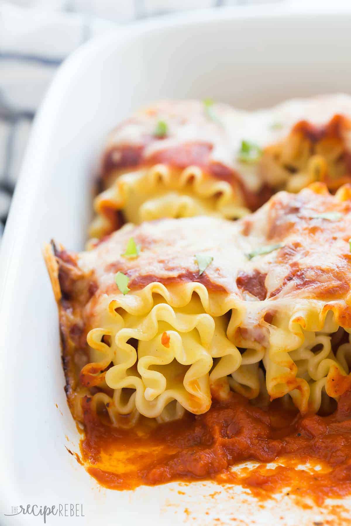 close up image of pepperoni pizza roll ups in white baking dish