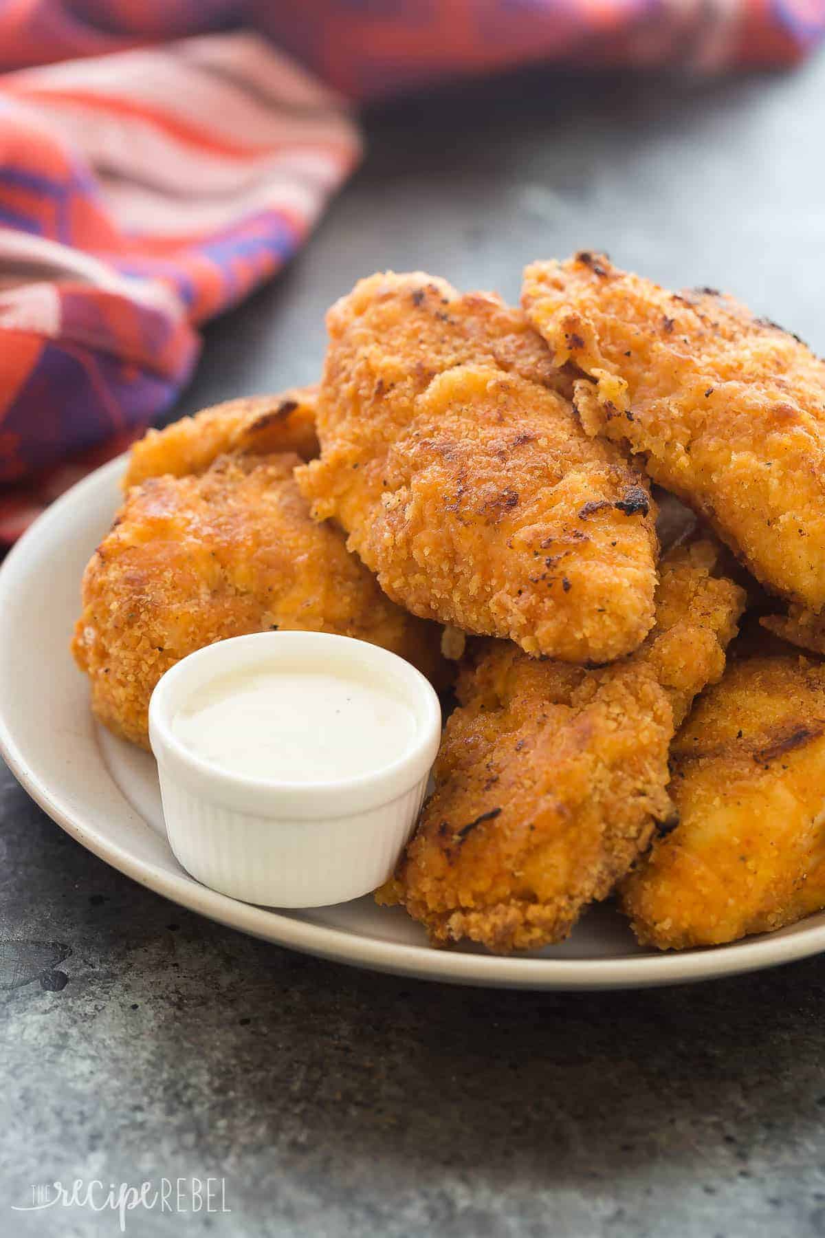 plate of oven fried chicken close up on dark grey background with red towel