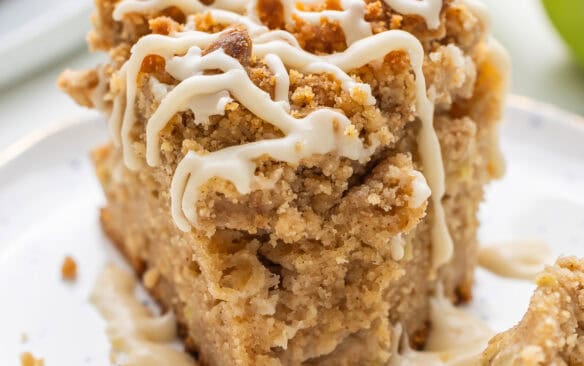 square image of slice of apple coffee cake on a plate.