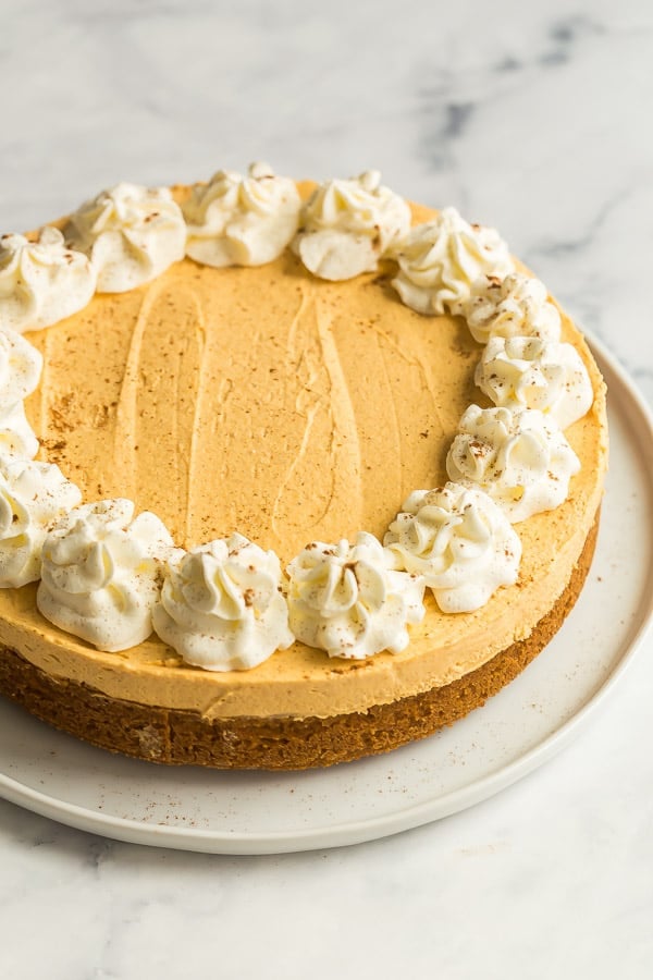 no bake pumpkin cheesecake whole on white plate with whipped cream