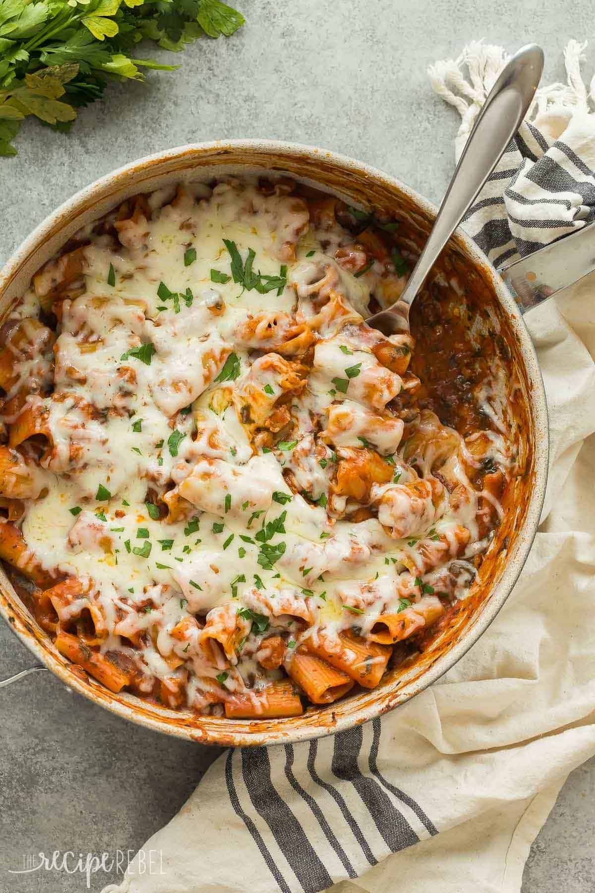 overhead image of large skillet with baked ziti and spoon stuck into pasta