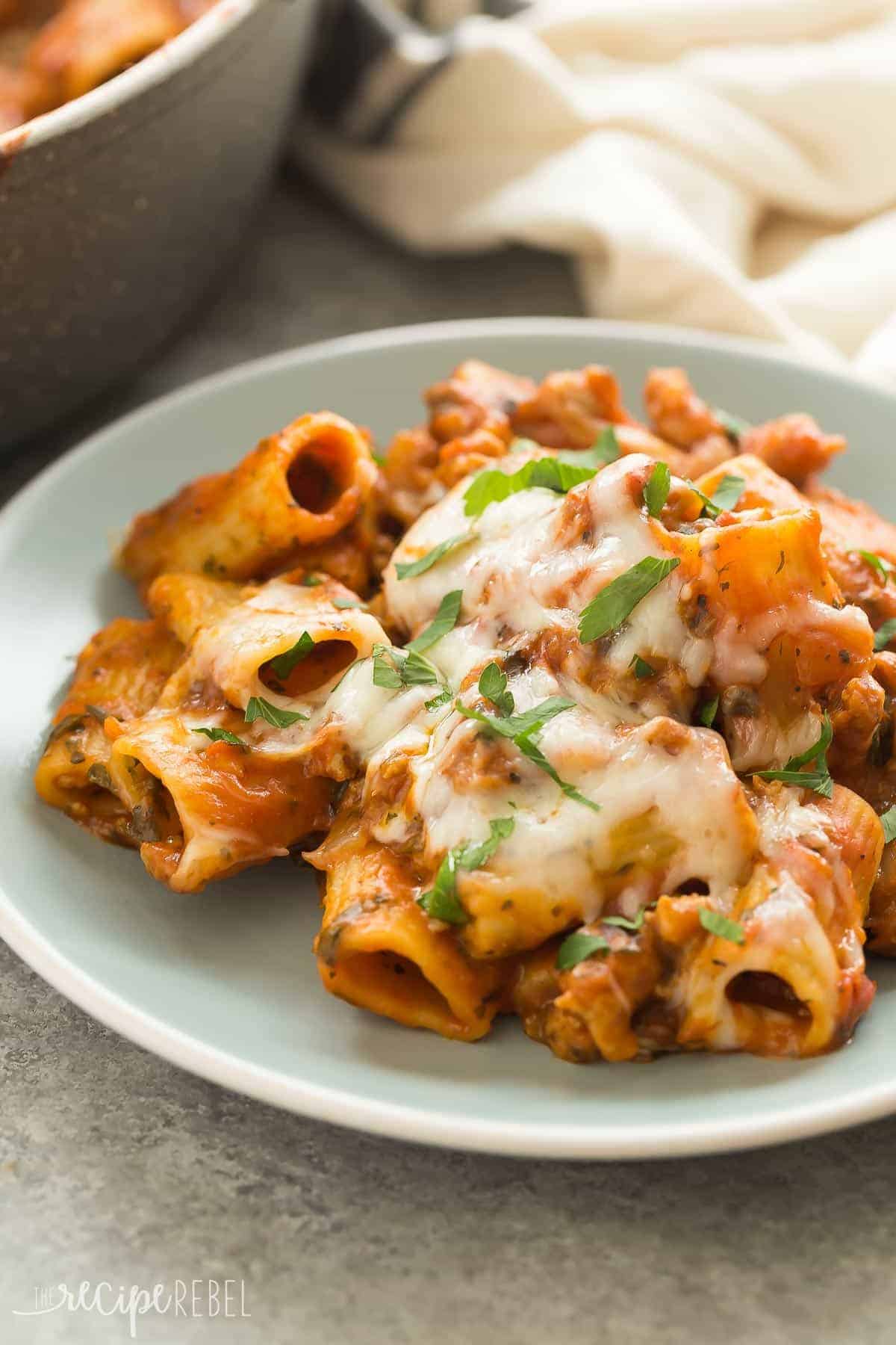 one pot baked ziti on blue plate with melted cheese and topped with fresh parsley