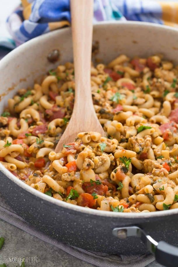 one pot turkey chili mac in grey pan with wooden spoon stuck in and blue towel in background