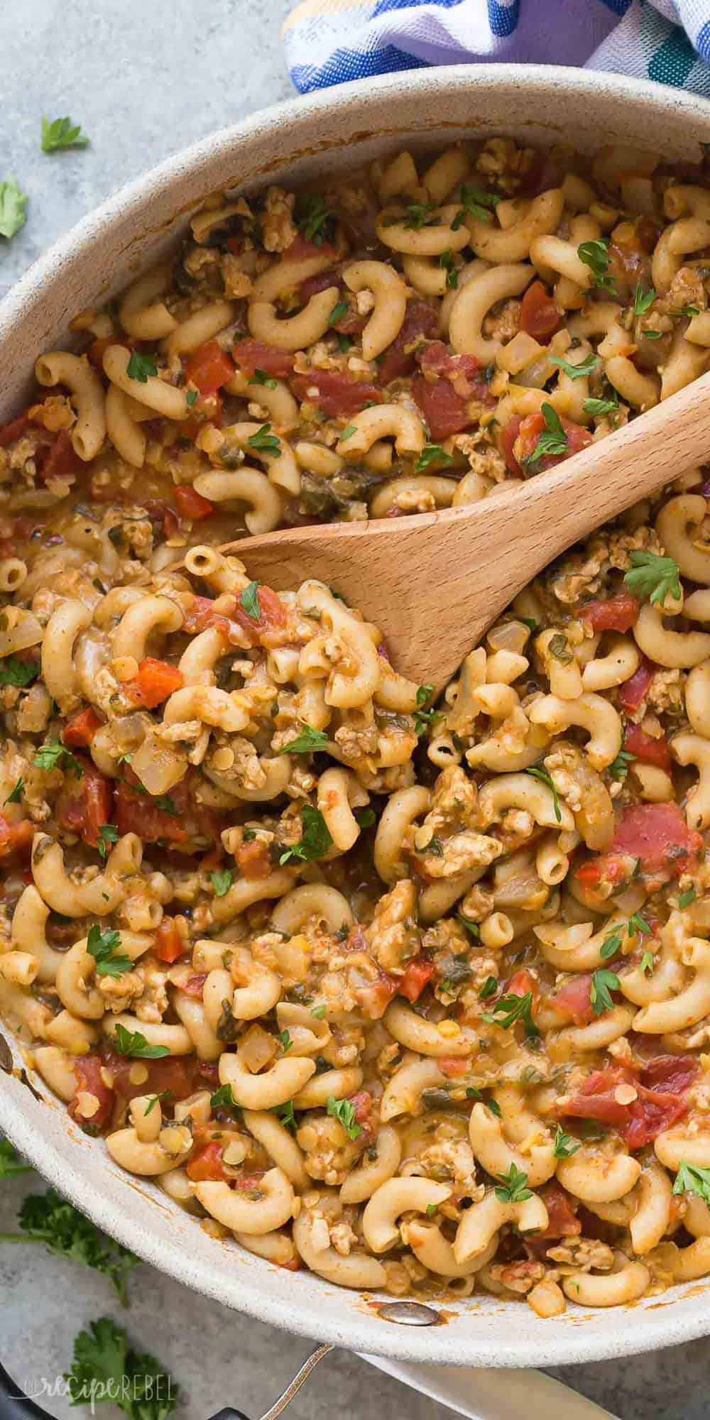 overhead long image of turkey chili mac in pan with wooden spoon