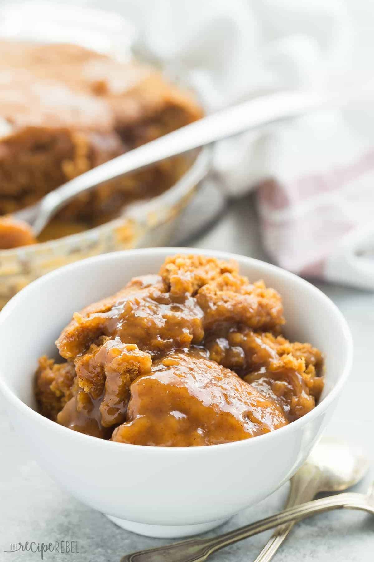 white bowl filled with pumpkin pudding cake with two spoons on the side