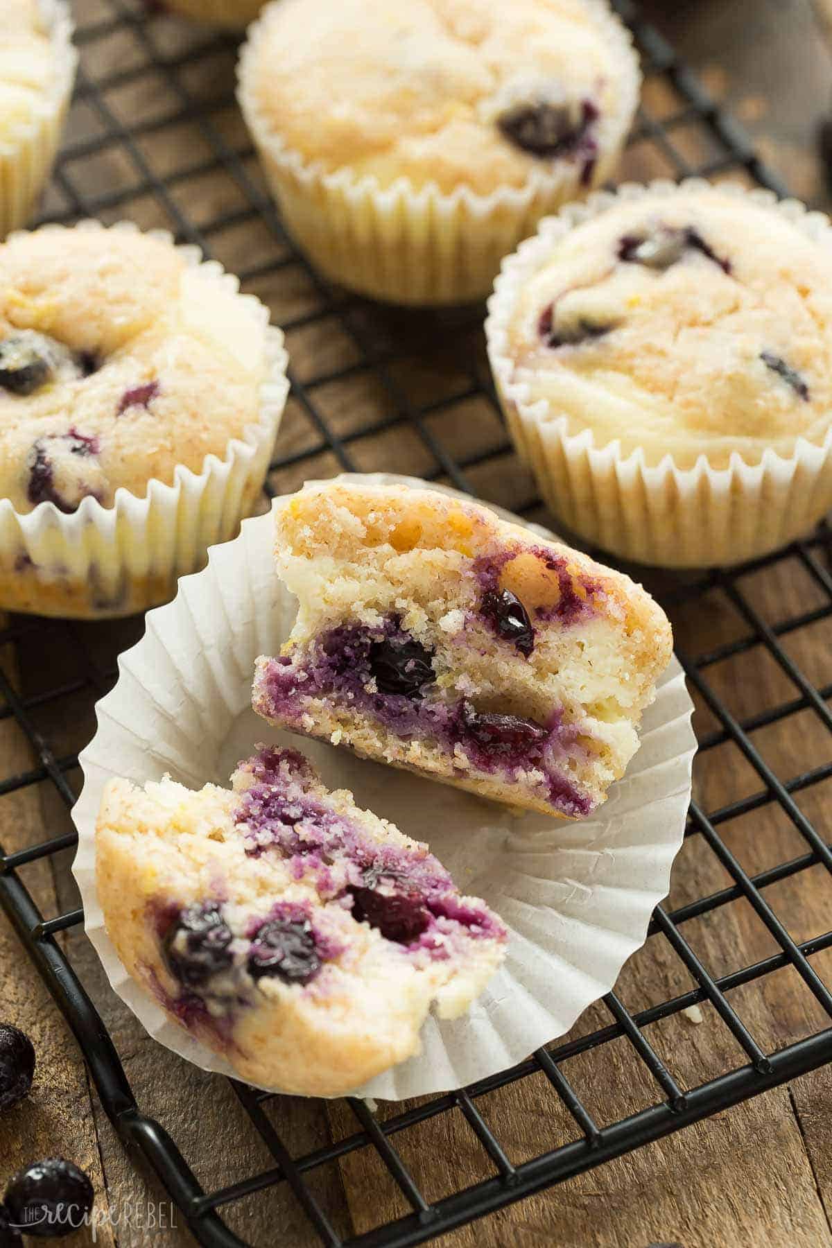 blueberry lemon muffins on cooling rack with one muffin cut in half