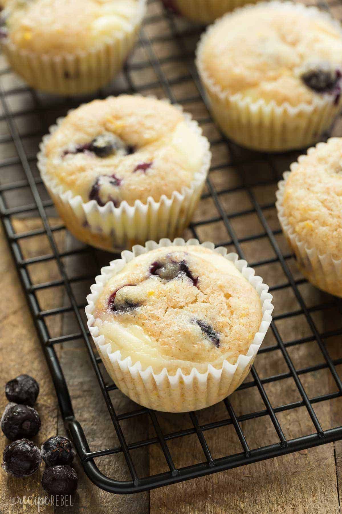 blueberry lemon muffins with cream cheese on black cooling rack on wooden background