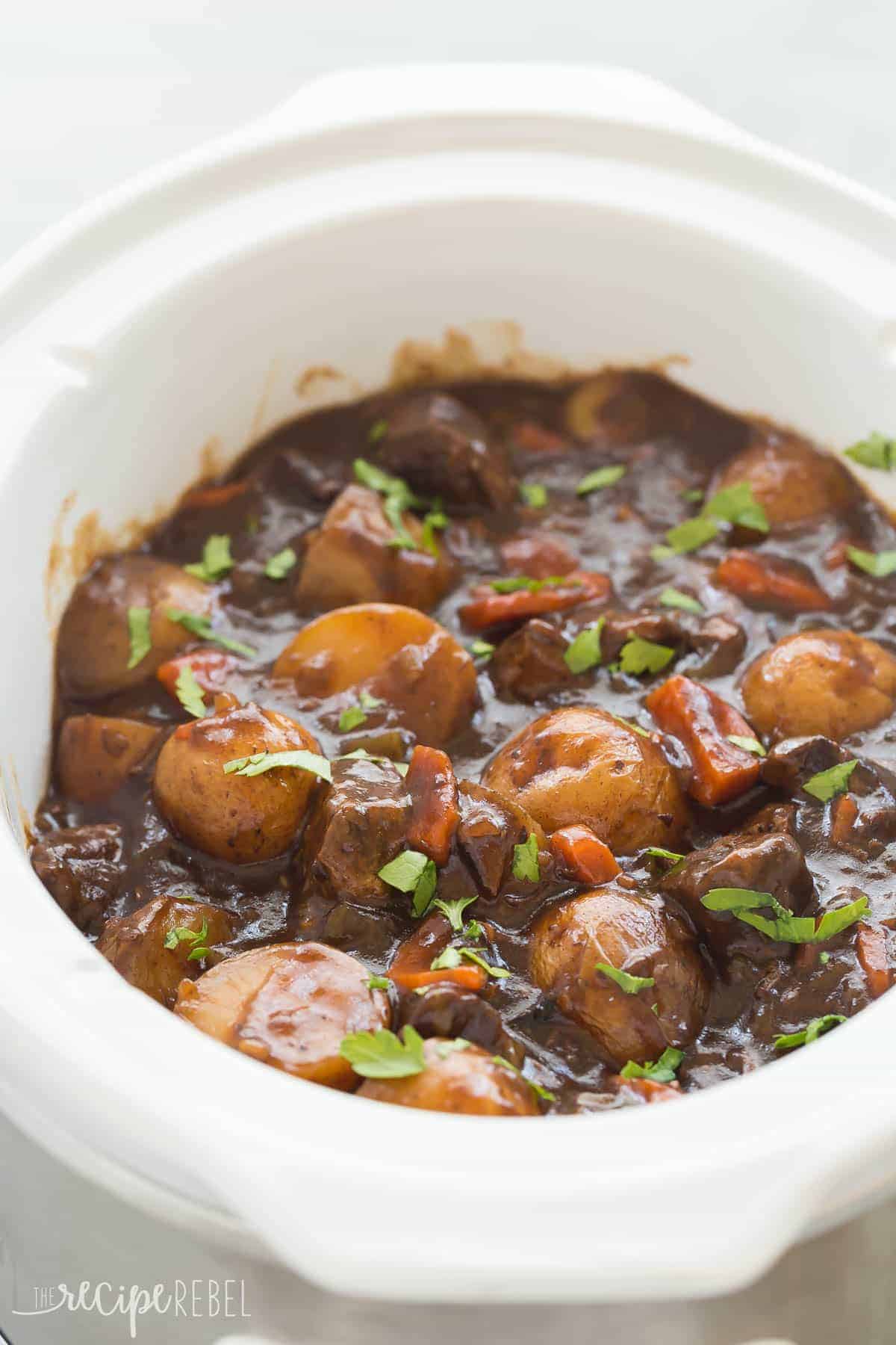 This Honey Balsamic Slow Cooker Beef Stew is full of flavor and couldn't be easier -- just throw everything in and let it cook! Loaded with veggies and thick honey balsamic sauce. Step by step recipe video. white crockpot with honey balsamic beef stew in it