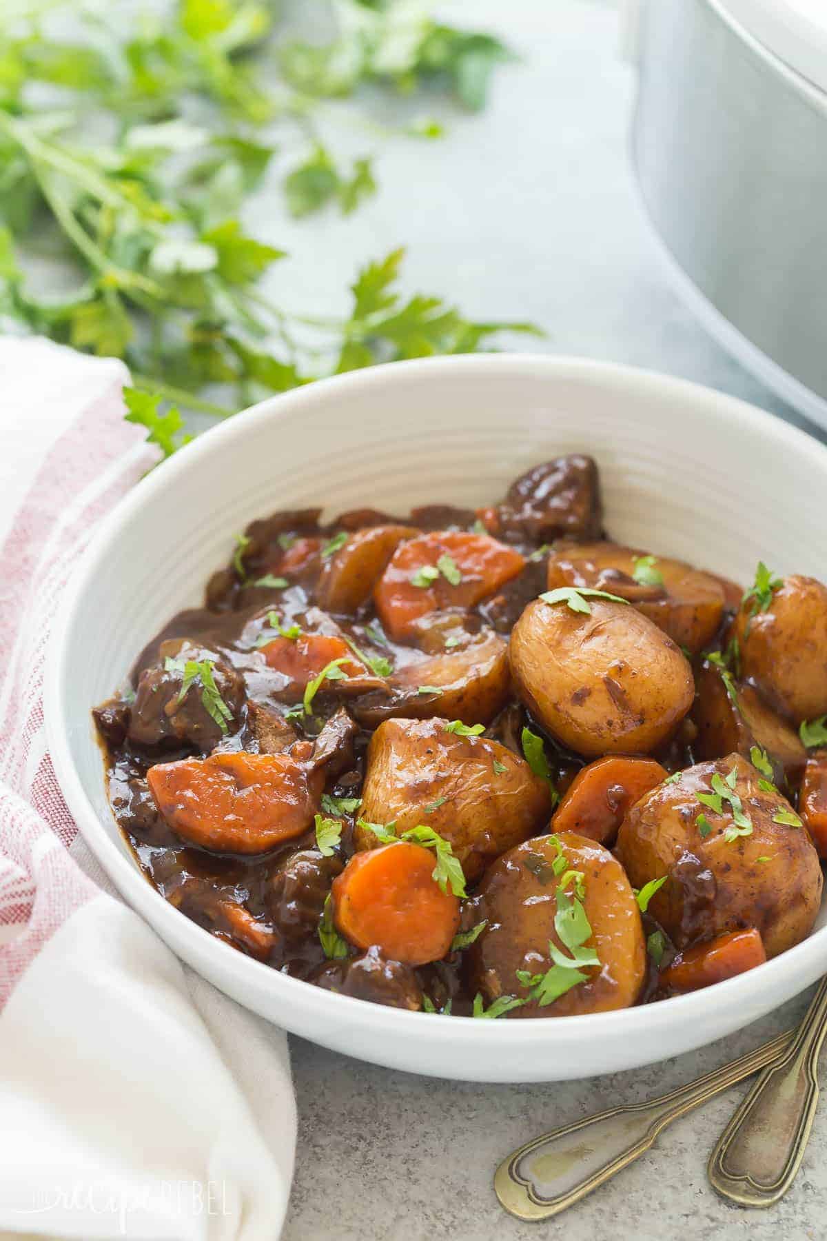 Honey Balsamic Slow Cooker Beef Stew in a white bowl with fresh herbs