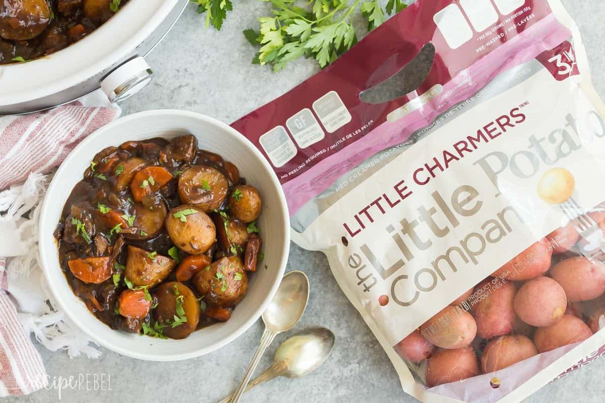 honey balsamic beef stew overhead in white bowl with bag of little potatoes on the side