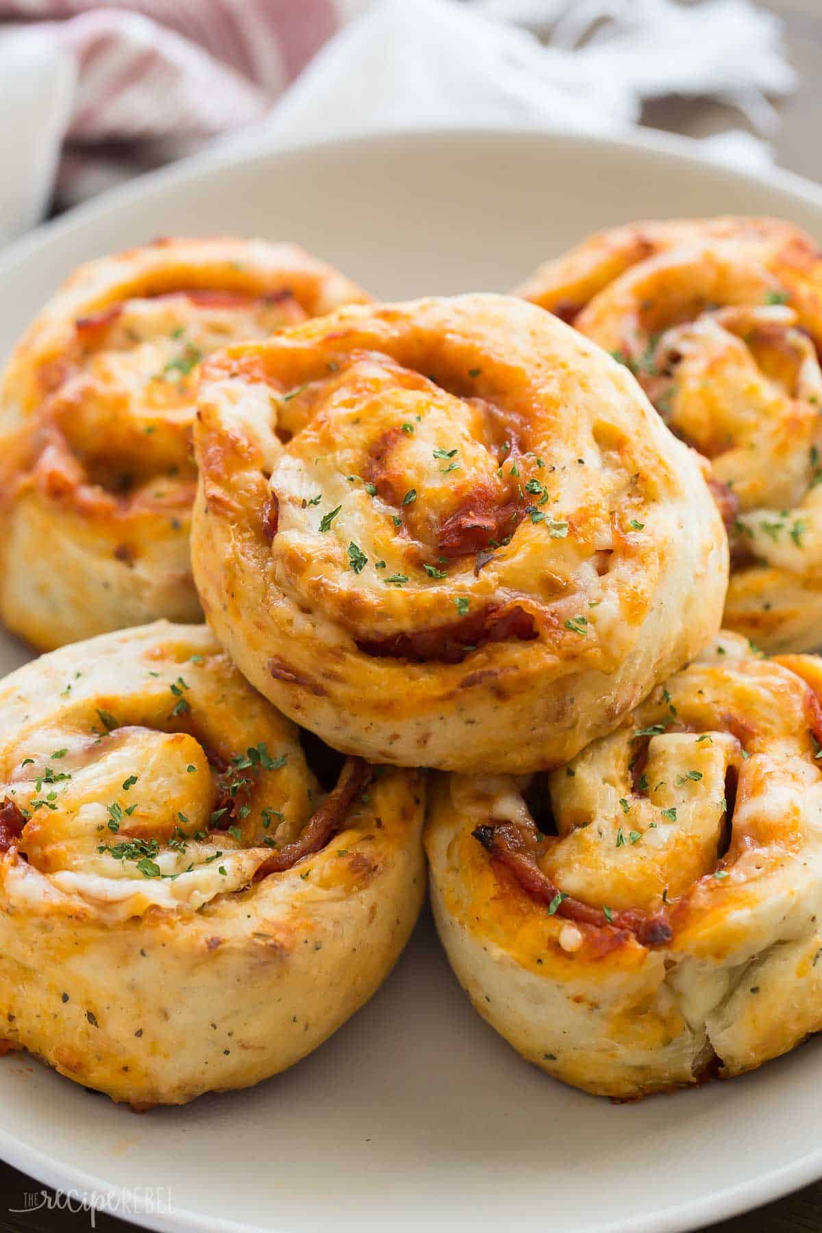 close up image of pizza pinwheels on plate with towel in the background