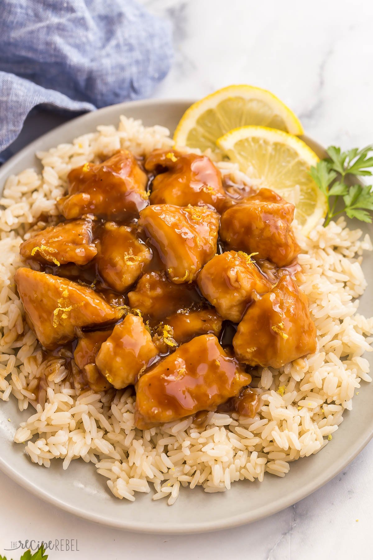 close up image of honey lemon chicken on rice with lemon slices