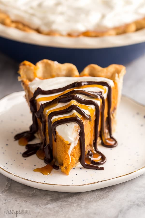 This Turtle Pumpkin Pie is made on a flaky pie crust, topped with pecans, caramel and a no bake pumpkin pie filling! Make it in a graham cracker or Oreo crust for a completely no bake Thanksgiving dessert! #pie #pumpkin #thanksgiving #dessert #pumpkinpie slice of turtle pumpkin pie on plate with chocolate and caramel drizzle