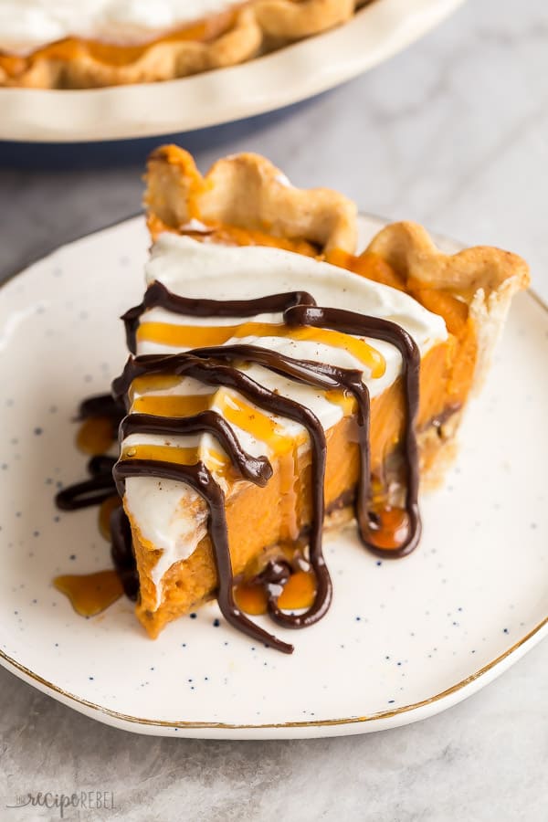 slice of pumpkin pie on white plate with chocolate and caramel drizzle