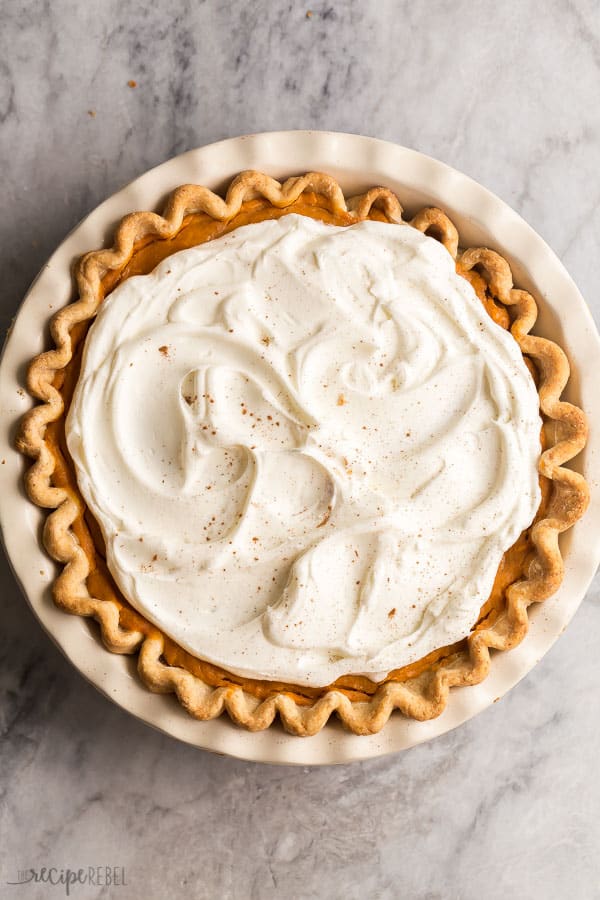 This Turtle Pumpkin Pie is made on a flaky pie crust, topped with pecans, caramel and a no bake pumpkin pie filling! Make it in a graham cracker or Oreo crust for a completely no bake Thanksgiving dessert! #pie #pumpkin #thanksgiving #dessert #pumpkinpie overhead image of turtle pumpkin pie with whipped cream