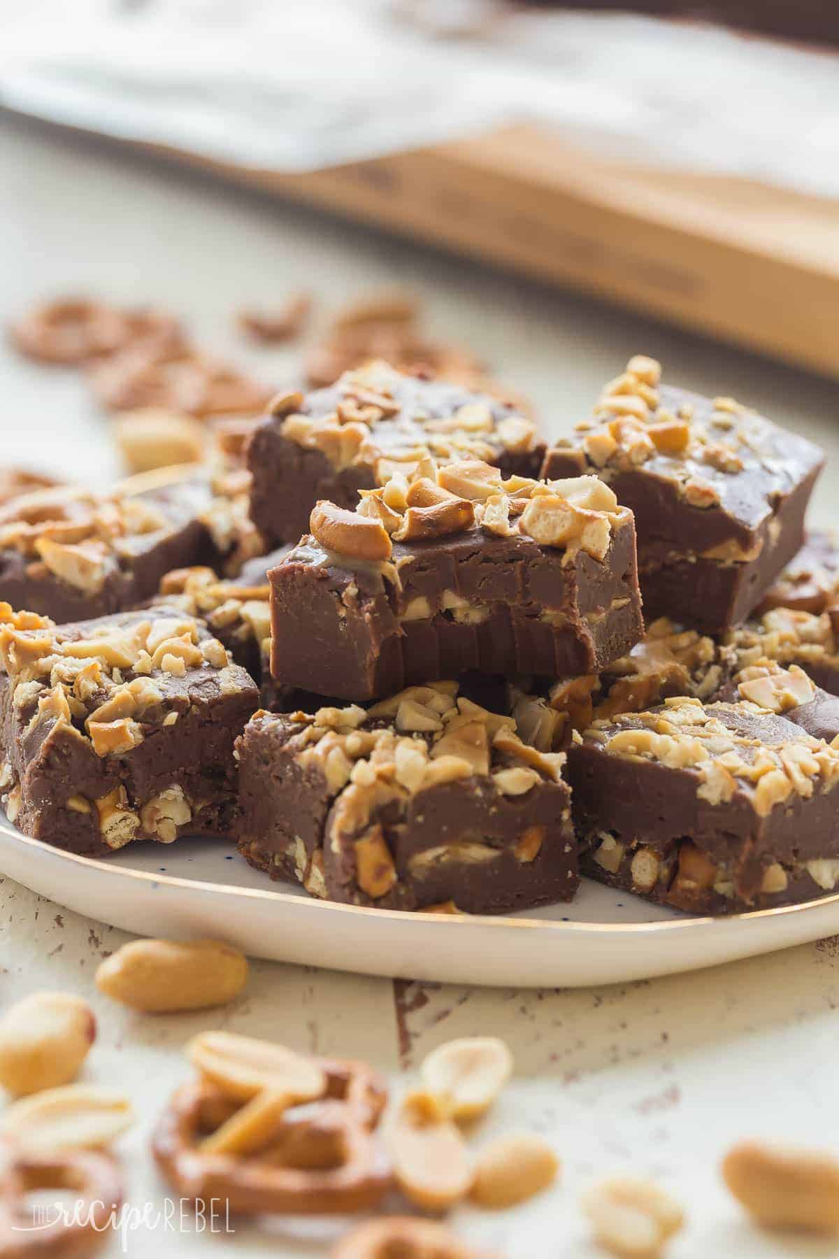 peanut butter chocolate fudge with pretzels and peanuts on white plate