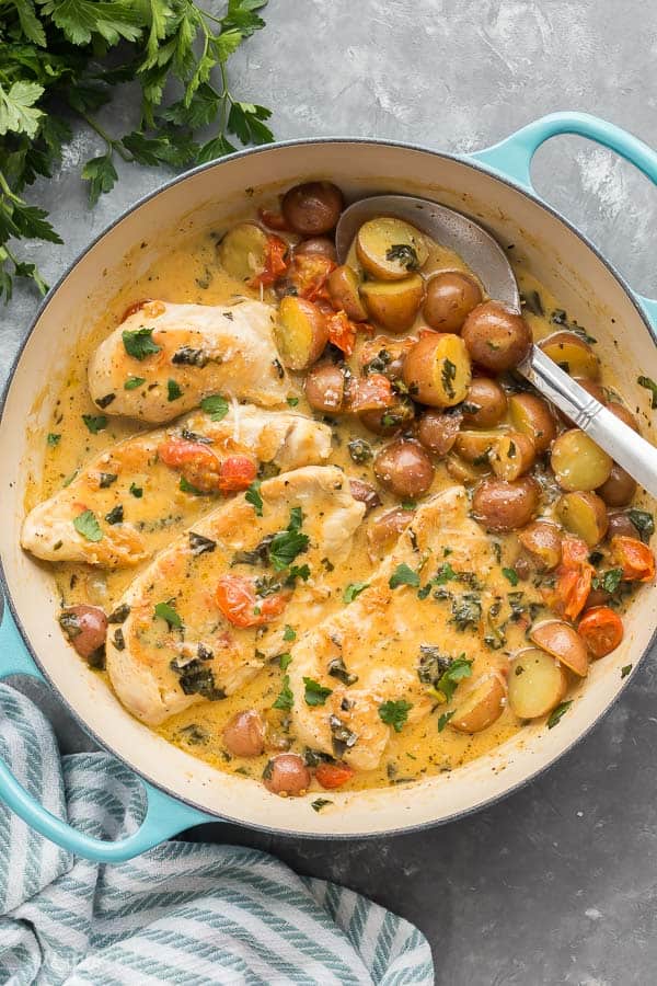 tuscan chicken and potato skillet overhead in white and blue skillet with metal spoon stuck into potatoes