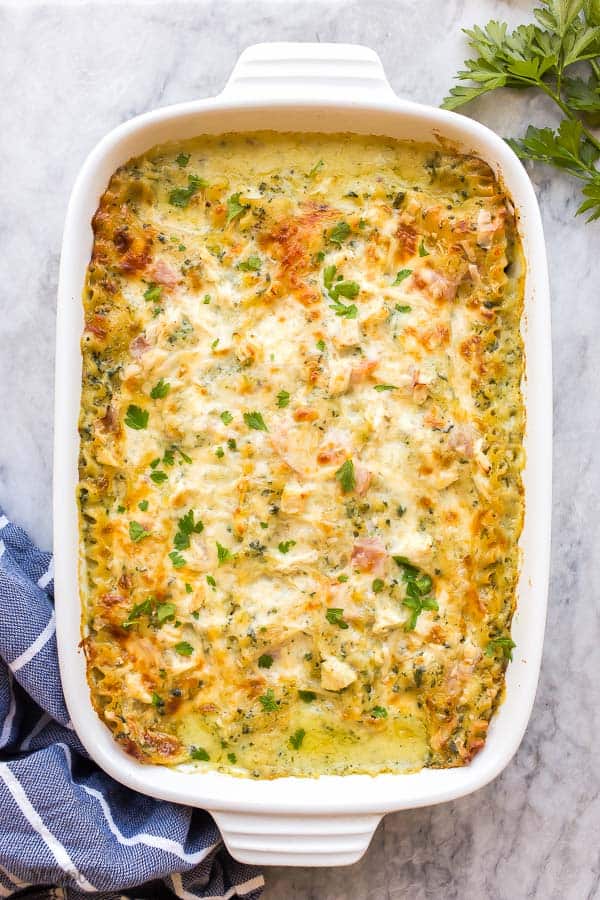 This White Chicken Lasagna with Ham and Spinach is the ULTIMATE comfort food! Made with a lighter Alfredo sauce, it's decadent enough for the holidays and still loaded with healthy ingredients. #lasagna #chicken #ham #pasta #dinner overhead image of white lasagna in white pan