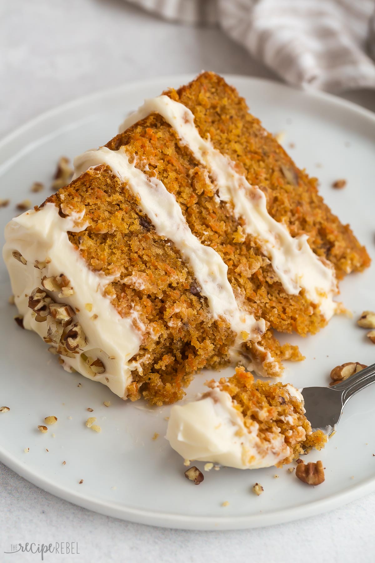 slice of carrot cake on plate with fork taking a bite