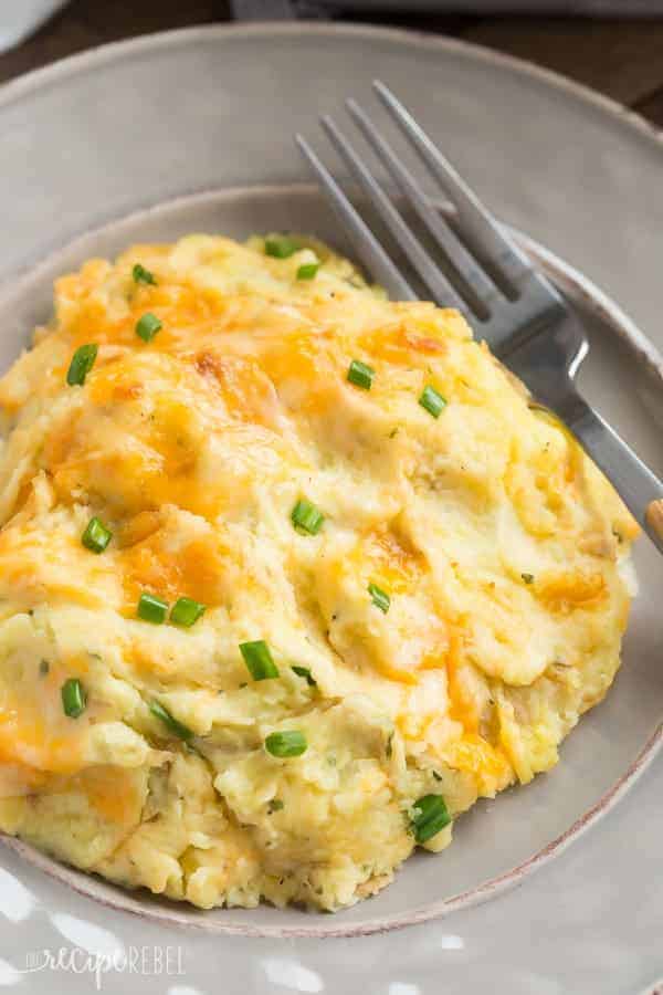grey plate with cheesy make ahead mashed potatoes topped with green onions