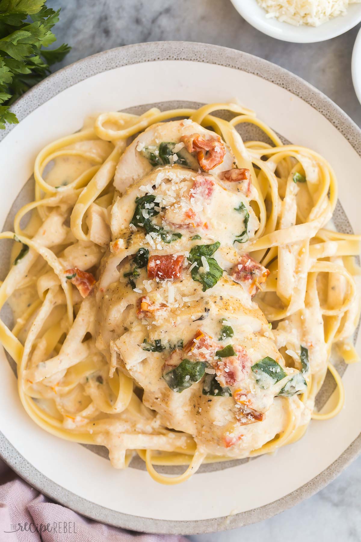 overhead image of crockpot tuscan chicken on plate of pasta