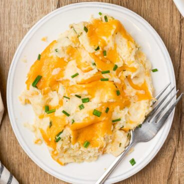 overhead image of plate of make ahead mashed potatoes with cheese on top