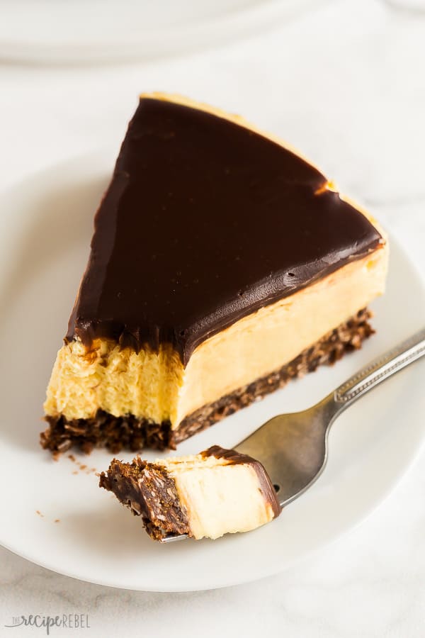 no bake nanaimo bar cheesecake slice on white plate with bite taken off of the end and chocolate ganache on top