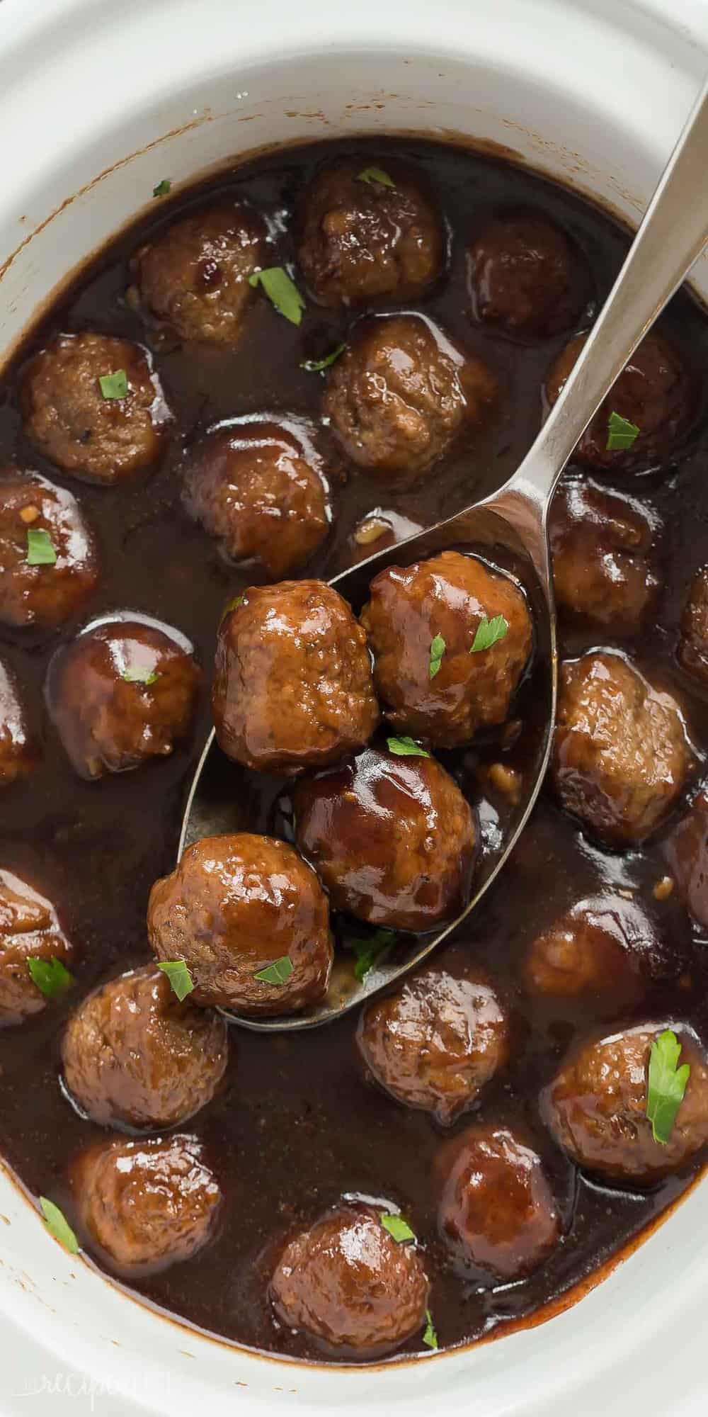 These Slow Cooker Cranberry Meatballs are sweet and tangy with a little spice -- the perfect holiday appetizer or easy weeknight dinner! Includes step by step recipe video overhead long image of cranberry meatballs in white crockpot