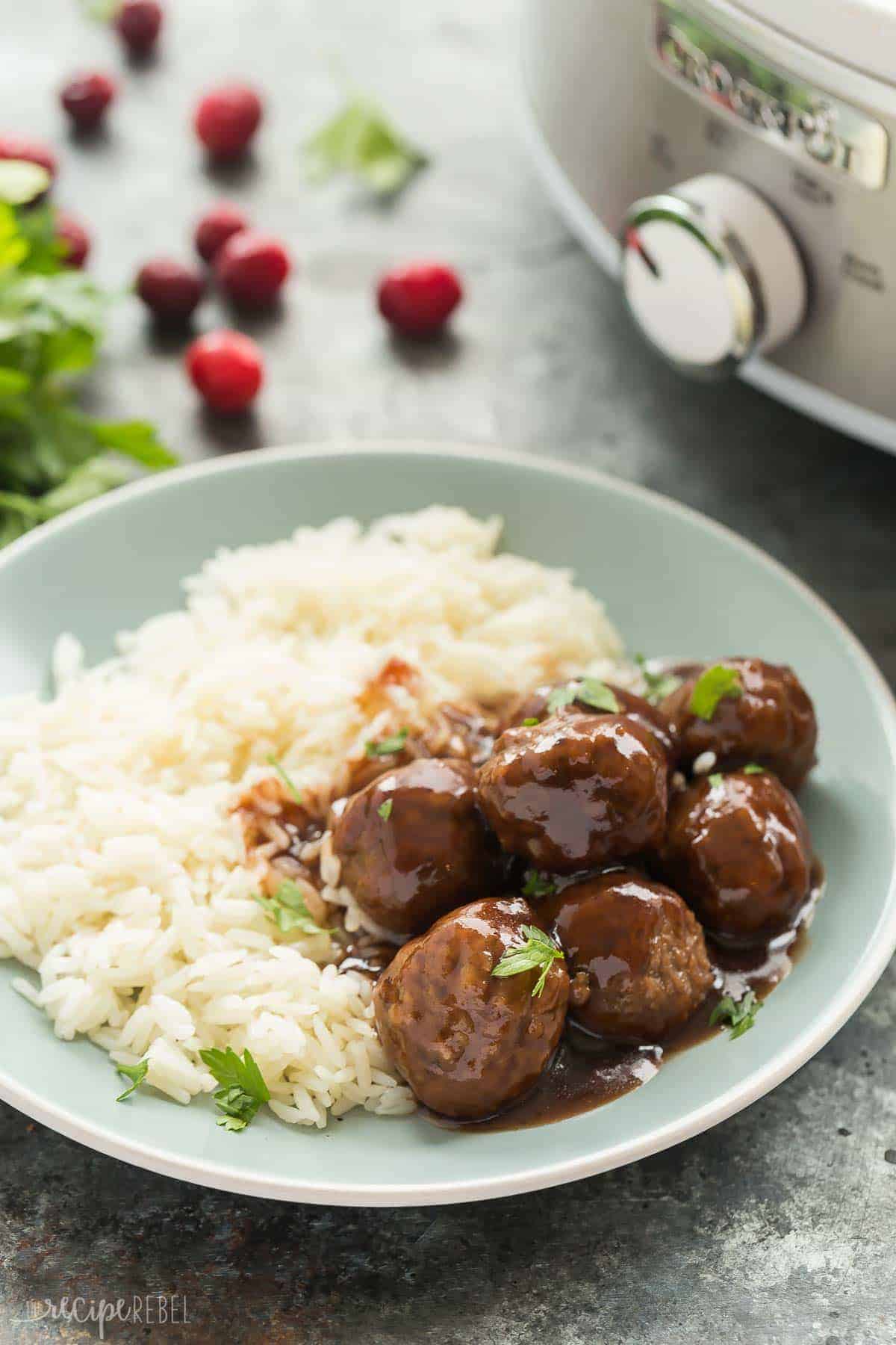 slow cooker cranberry meatballs on rice on light blue plate with crockpot in the background