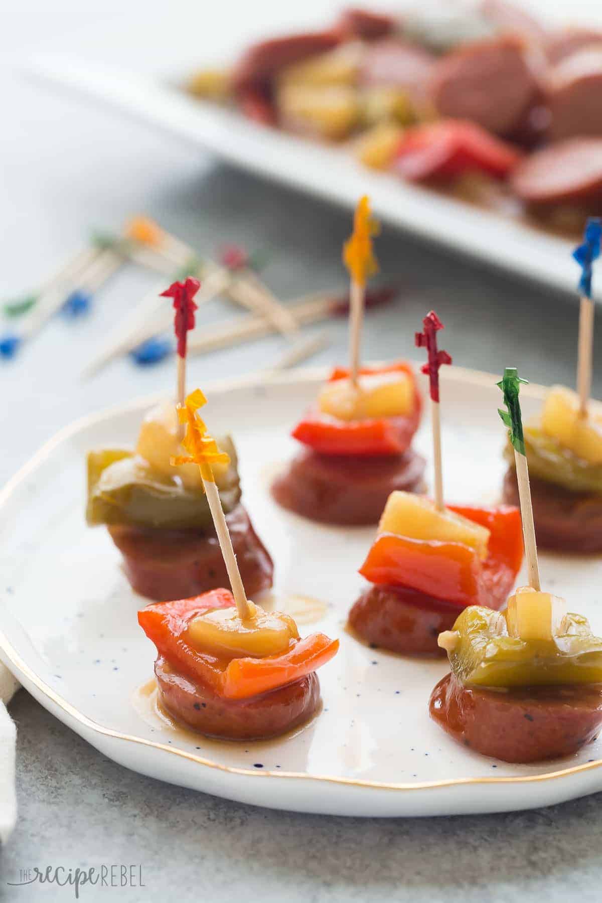 a white plate with sliced smokies and peppers on fancy toothpicks