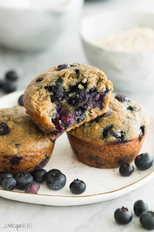 healthy blueberry oatmeal muffins on white plate with bite taken out of one