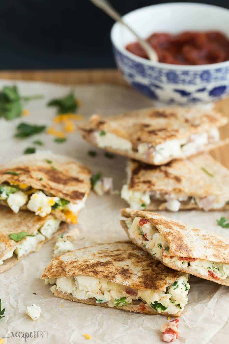 close up image of triangle pieces of breakfast quesadillas on parchment