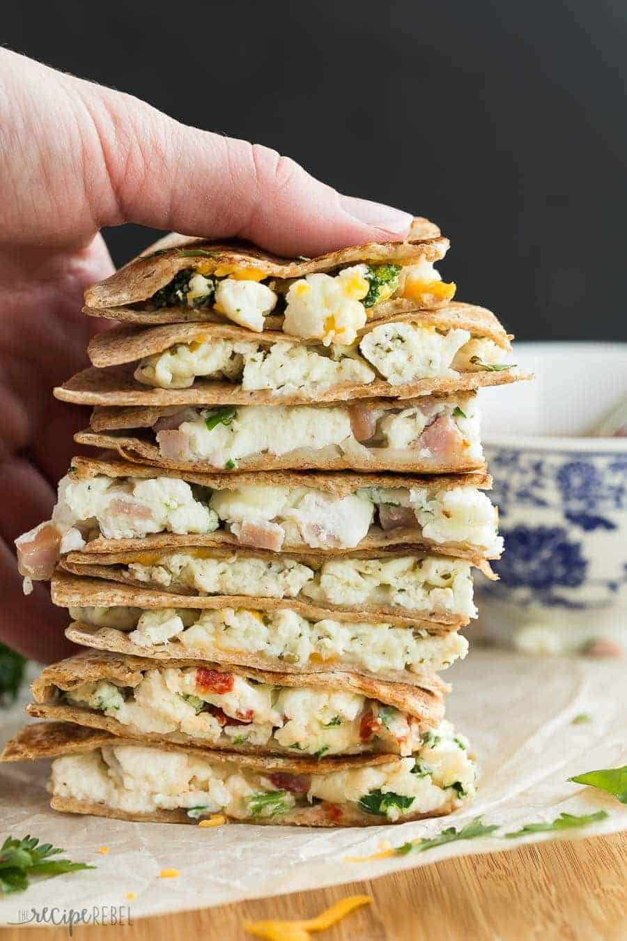 tall stack of make ahead breakfast quesadillas on parchment on wooden cutting board