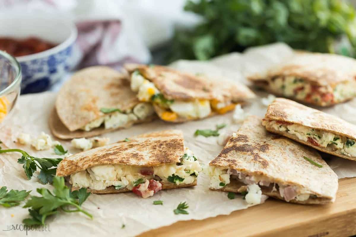 breakfast quesadillas cut in triangles on parchment on wood cutting board