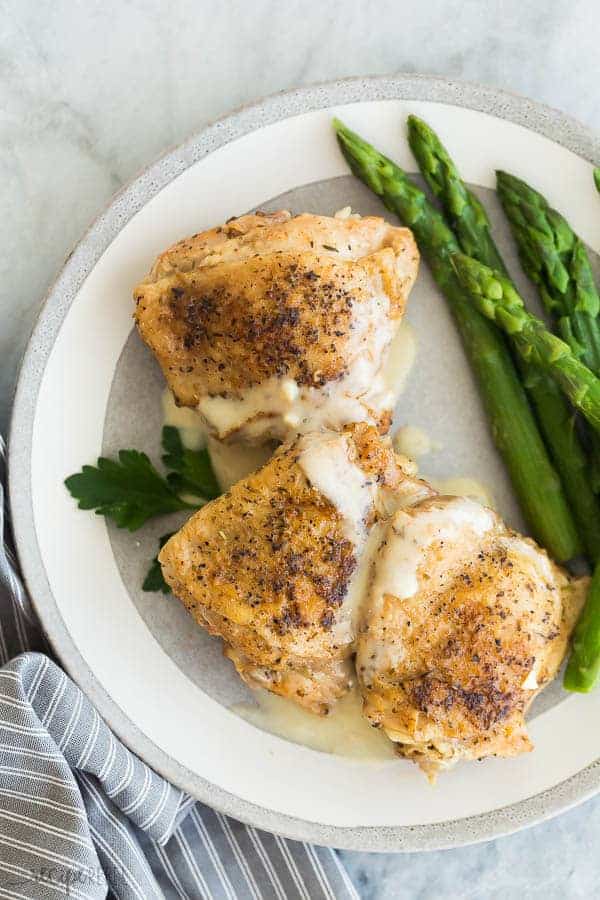 garlic instant pot chicken thighs overhead on grey plate with asparagus
