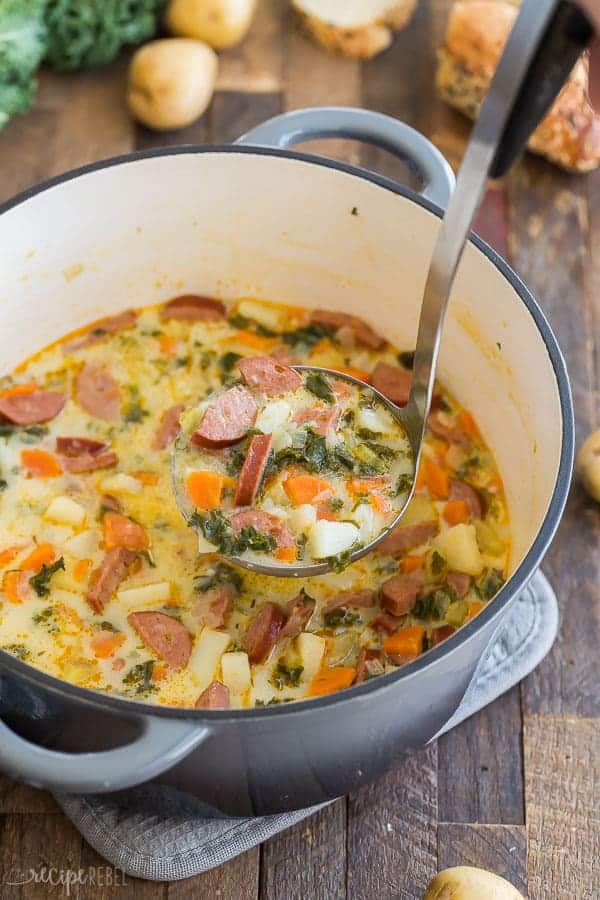 sausage potato soup with kale in pot with metal scoop scooping some soup