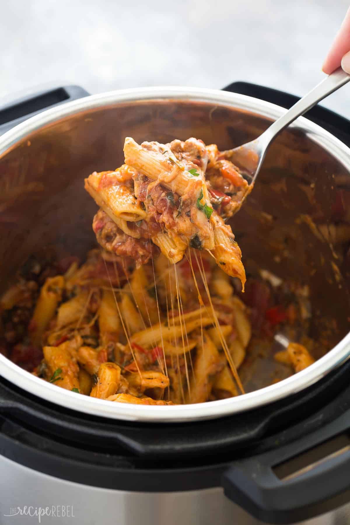 easy instant pot baked ziti being scooped out of pressure cooker on a metal spoon