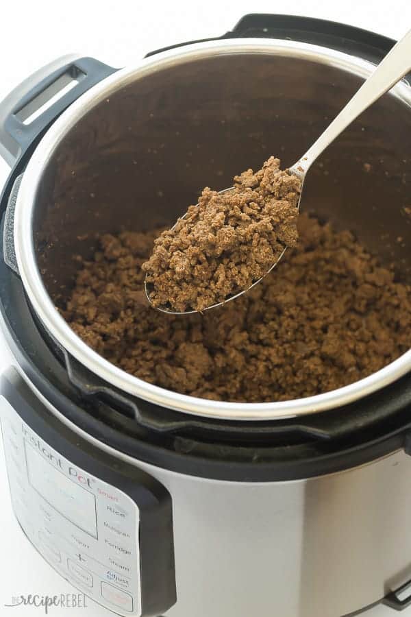 instant pot taco meat in pressure cooker being scooped out with metal spoon