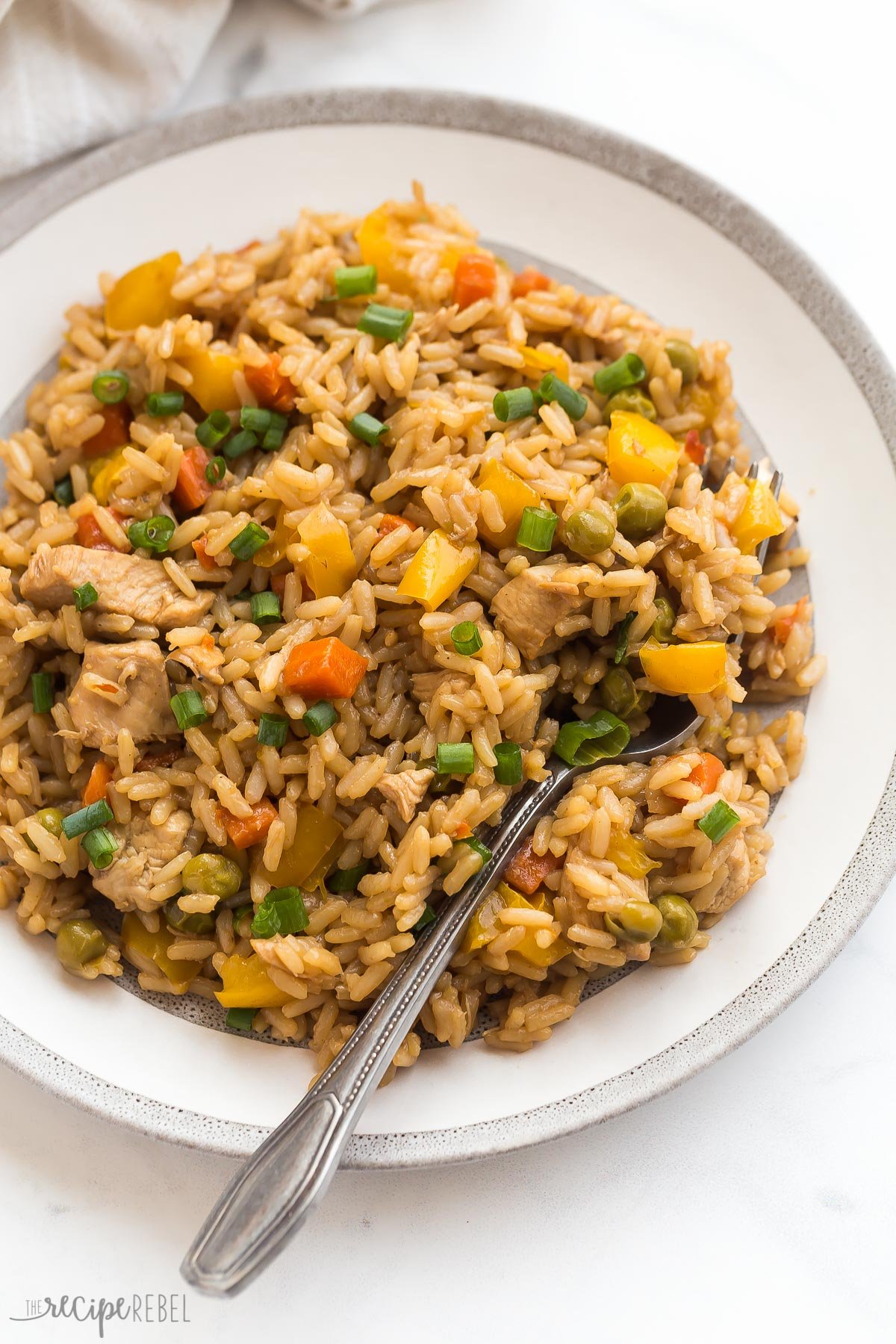 This Instant Pot Teriyaki Chicken and Rice is an easy dinner recipe made completely in one pot! Loaded with vegetables and covered in a sweet, tangy teriyaki sauce that cooks all together. A healthy dinner that comes together in minutes with no extra pots! #instantpot #chicken #recipes | easy instant pot recipes | chicken dinner | chicken and rice | healthy dinner | easy recipes | pressure cooker instant pot teriyaki chicken and on a white plate with fork