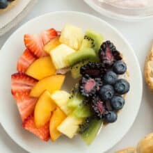 These Rainbow Bagel Fruit Pizzas with Strawberry Cream Cheese Spread are a fun breakfast or snack! Topped with a homemade, naturally sweetened strawberry cream cheese spread and fresh fruit that the kids (and the rest of the family!) will love! A fun treat for Easter, St. Patrick's Day or any day! Includes step by step recipe video. #rainbowfood rainbow food #fruit #breakfast #brunch #creamcheese