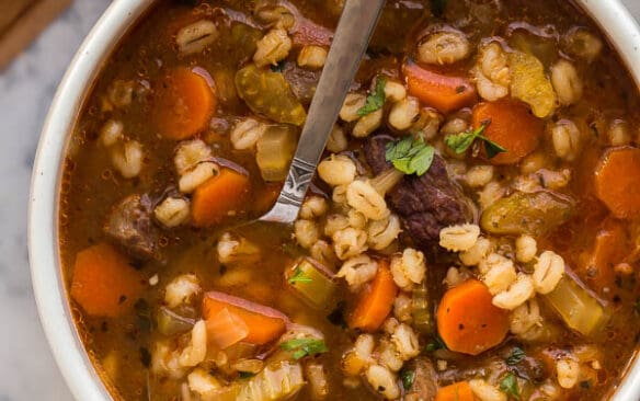 overhead image of beef barley soup with spoon in bowl