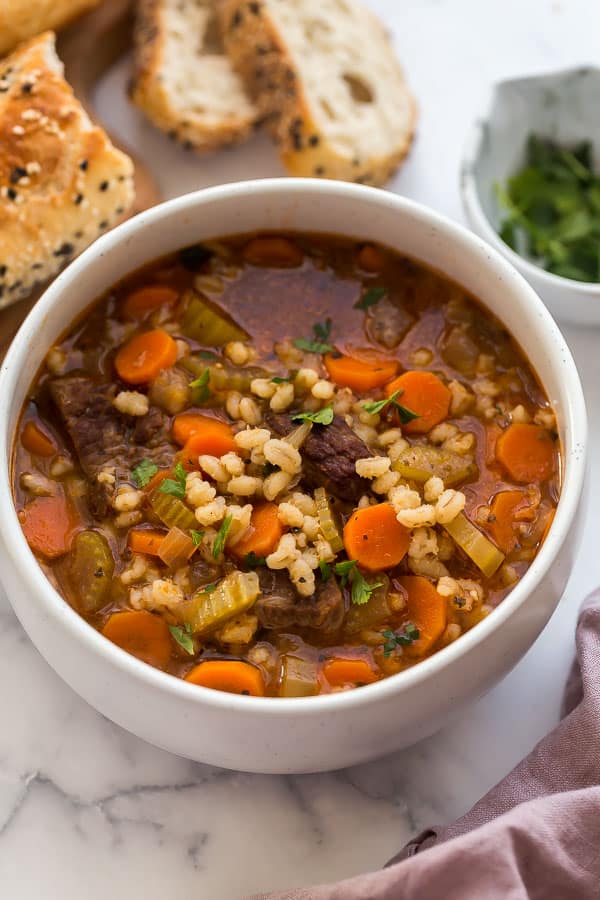 close up image of beef and barley soup in white bowl
