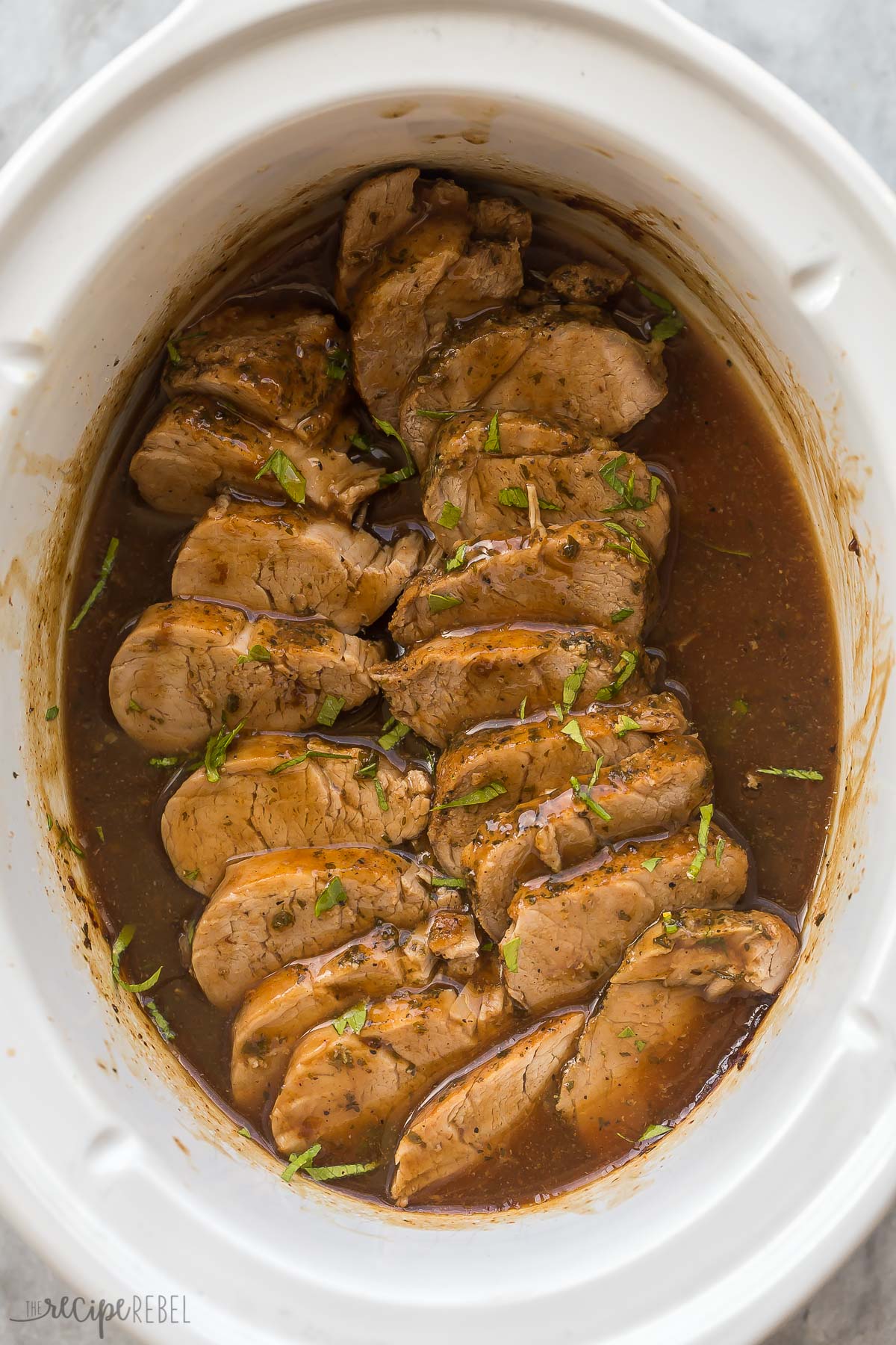 slow cooker pork tenderloin slice in crockpot with sauce