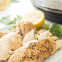 Instant Pot Whole Chicken on a white plate |This Instant Pot Whole Chicken recipe can be made with fresh or frozen chicken! It is moist, juicy and so much easier than roasting! Slathered in garlic butter and cooked to perfect in your pressure cooker in just 30 minutes.