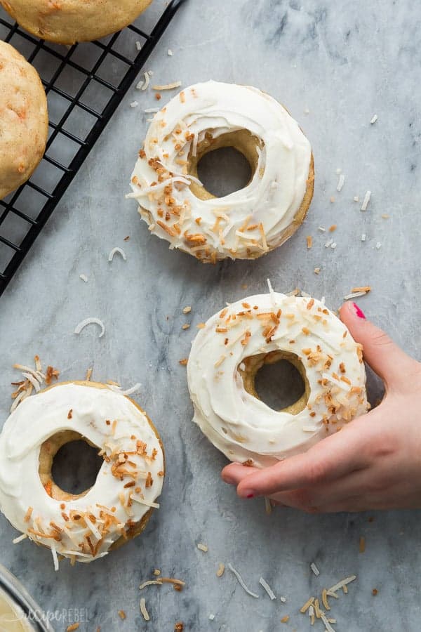carrot cake donuts with cream cheese frosting on marble with child's hand