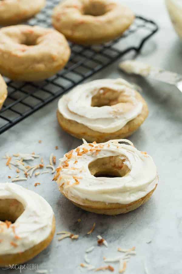 carrot cake baked donuts on marble with cream cheese frosting and toasted coconut