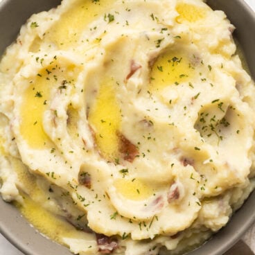 overhead image of mashed potatoes with melted butter in grey bowl.
